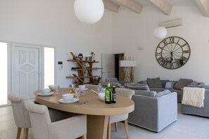 Ein modernes Wohnzimmer mit einem runden Esstisch, grauen Sofas und einer großen Wanduhr.