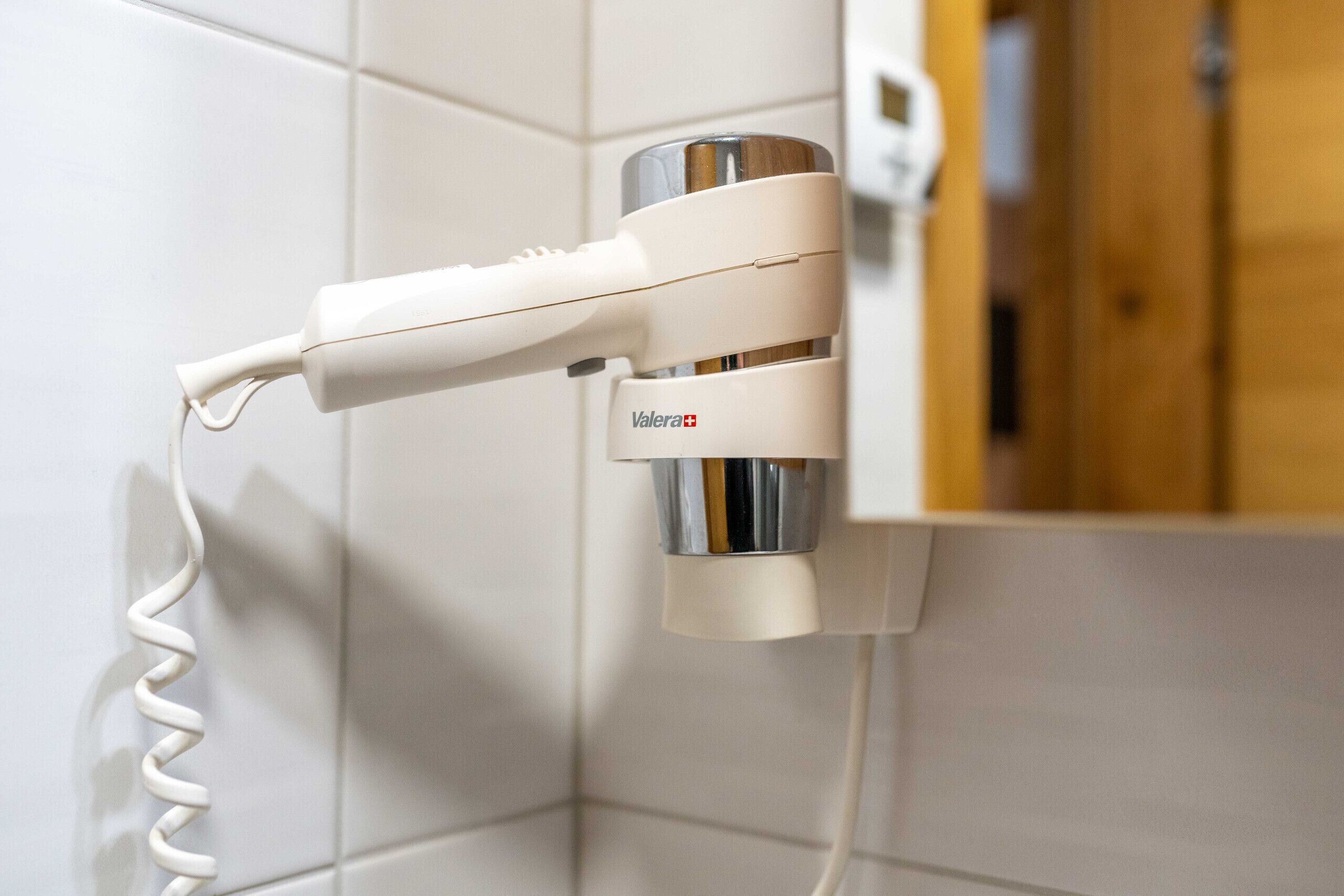 A bathroom with a white towel rack and a Valera+ hairdryer.
