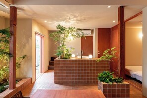 Ein modernes Badezimmer mit Fliesenboden, Waschbecken und Duschbereich. Pflanzen und Holzelemente prägen den Raum.