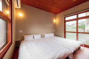 Hotellihuone, jossa on suuri sänky, puinen katto ja ikkuna, josta on näkymä rakennuksiin.