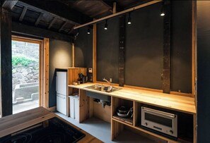 Uma cozinha compacta com bancada de madeira, pia, forno embutido e janela que traz luz natural.