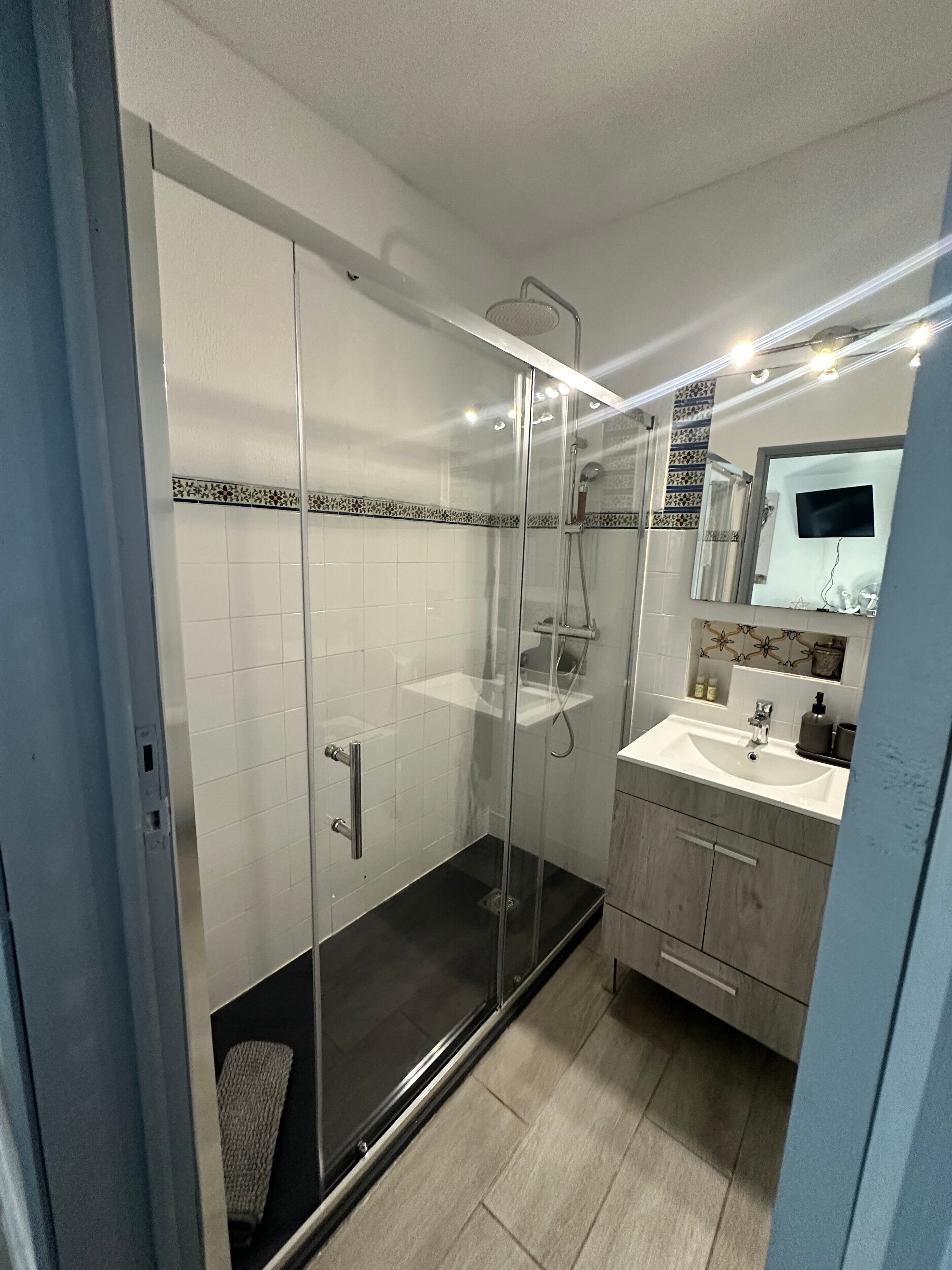 A modern bathroom with a glass-enclosed shower, a vanity with a sink, and a mirror above the sink.