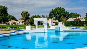 Una piscina dal design moderno, circondata da lettini e palme.