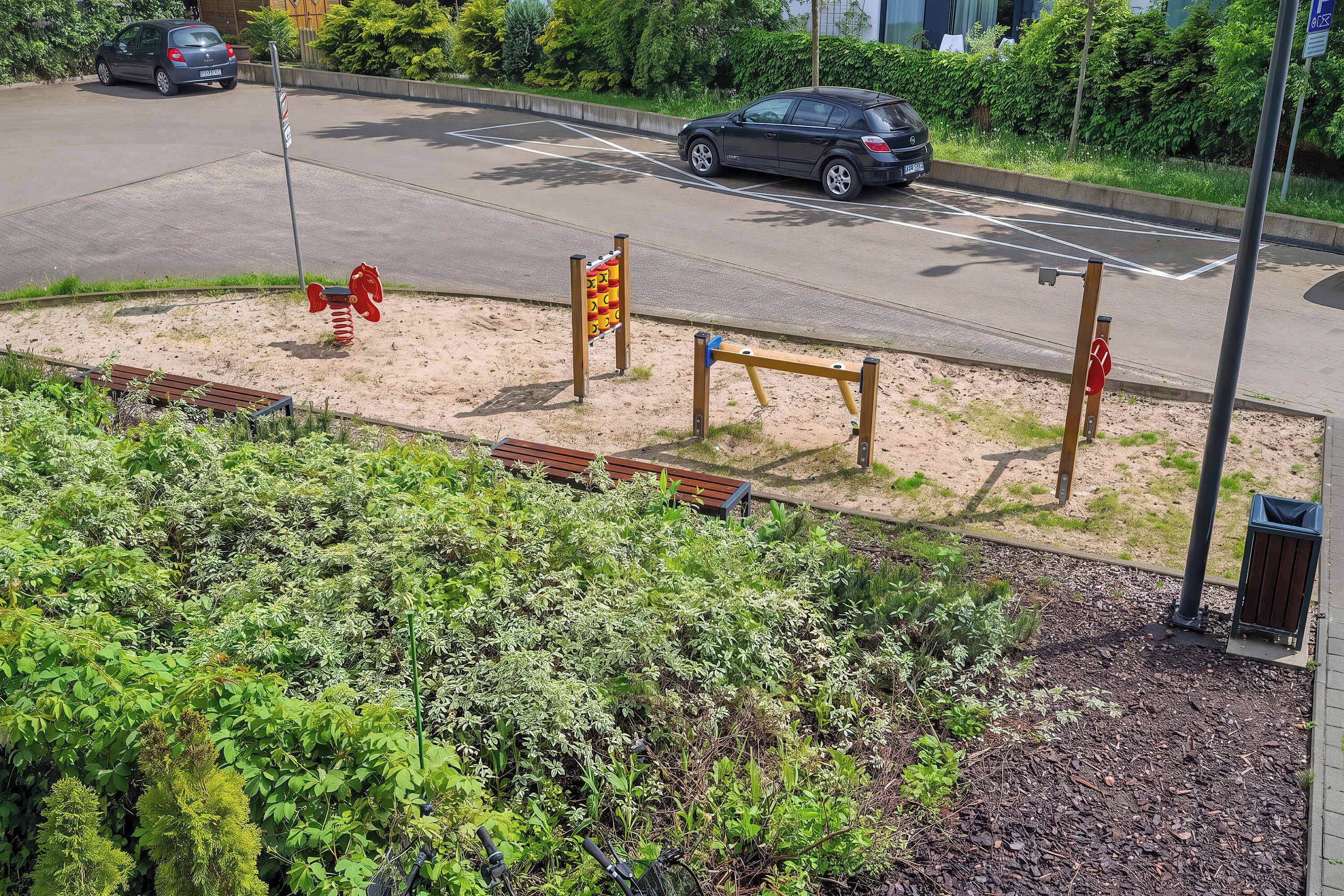 A parking lot with cars, a playground with swings, and a bench.