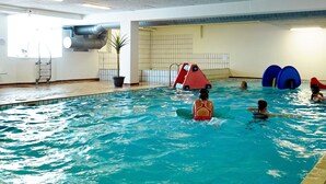 Ein Hallenbad mit freiem Blick auf den Poolbereich, einschließlich Wasser, Liegefläche und umliegenden Wänden.