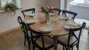 A dining area with a round table set for six, surrounded by black chairs with woven seats. - La Mémère bed and breakfast (Le Thillot)