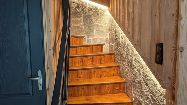 A wooden staircase with a stone wall on one side and a blue door on the other. - La Mémère bed and breakfast (Le Thillot)
