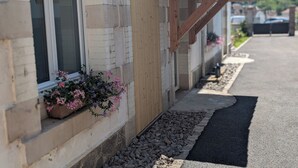 A building with a tiled roof, a window with a flower box, and a gravel pathway. - La Mémère bed and breakfast (Le Thillot)