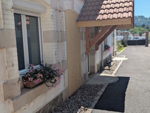 A building with a tiled roof, a window with a flower box, and a gravel pathway. - La Mémère bed and breakfast (Le Thillot)