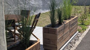 A modern building with a sloped roof, wooden planters with plants, and a clear view of a hilly landscape. - La Mémère bed and breakfast (Le Thillot)