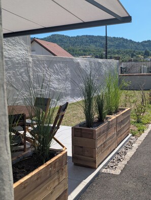A modern building with a sloped roof, wooden planters with plants, and a clear view of a hilly landscape. - La Mémère bed and breakfast (Le Thillot)