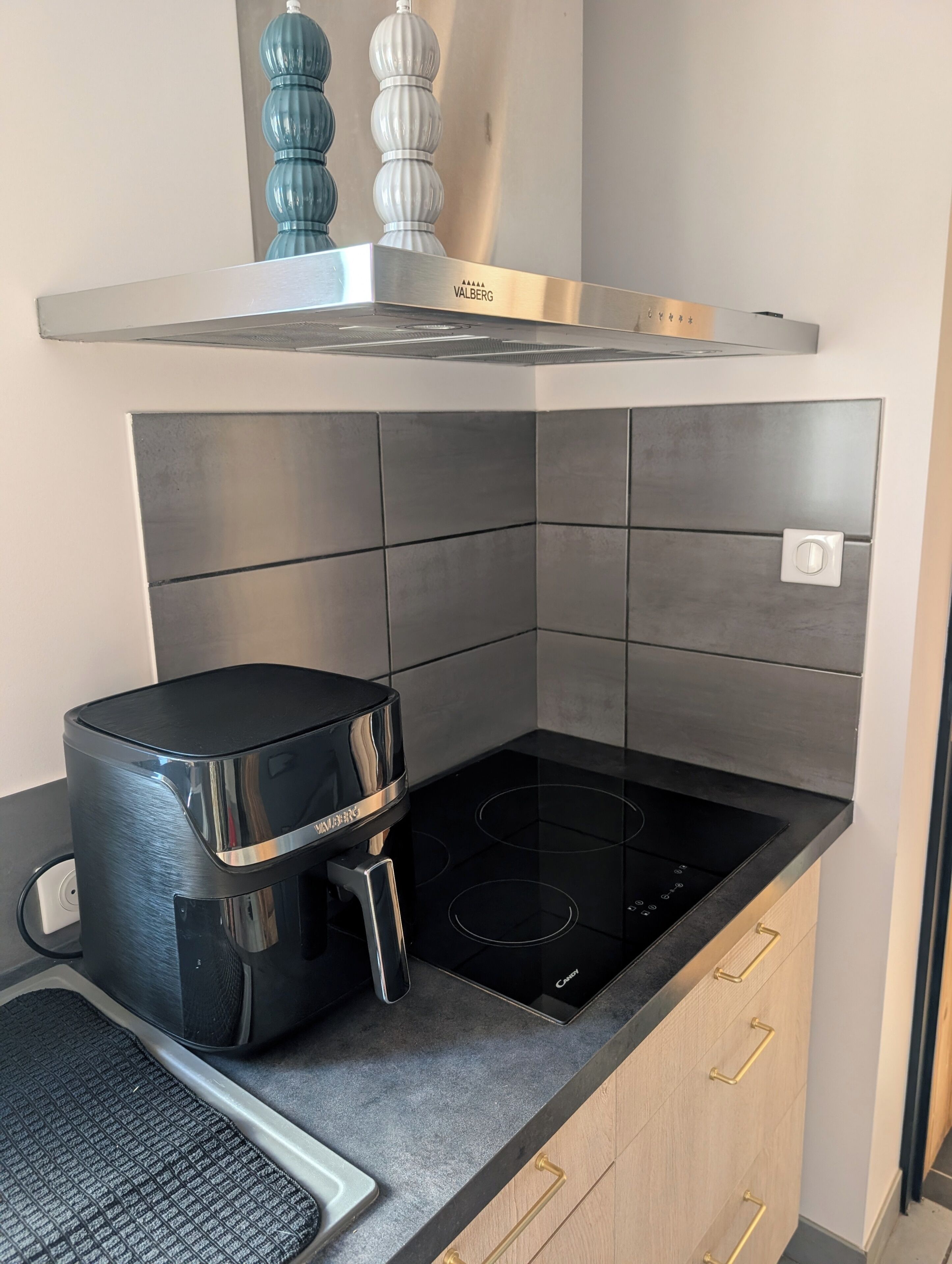 A kitchen with a built-in stove, a coffee maker, and a stainless steel range hood.