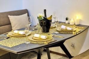 Mesa de jantar posta com detalhes dourados, uma garrafa de champanhe e velas.