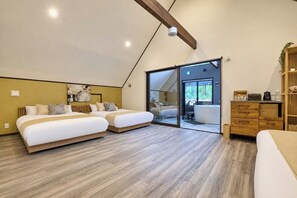 Ein modernes Schlafzimmer mit zwei Betten, einer Holzkommode, einer Glastür mit Schieberiegel, die auf einen Balkon führt, und einer Deckenleuchte.