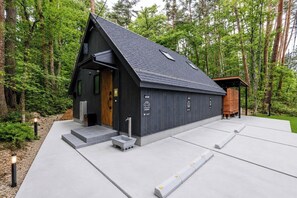 Ein modernes Gebäude mit Satteldach, einer Holztür und einer Betonrampe zum Eingang.