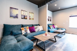 Ein modernes Wohnzimmer mit einer Eckcouch, zwei Couchtischen und Wandbildern.