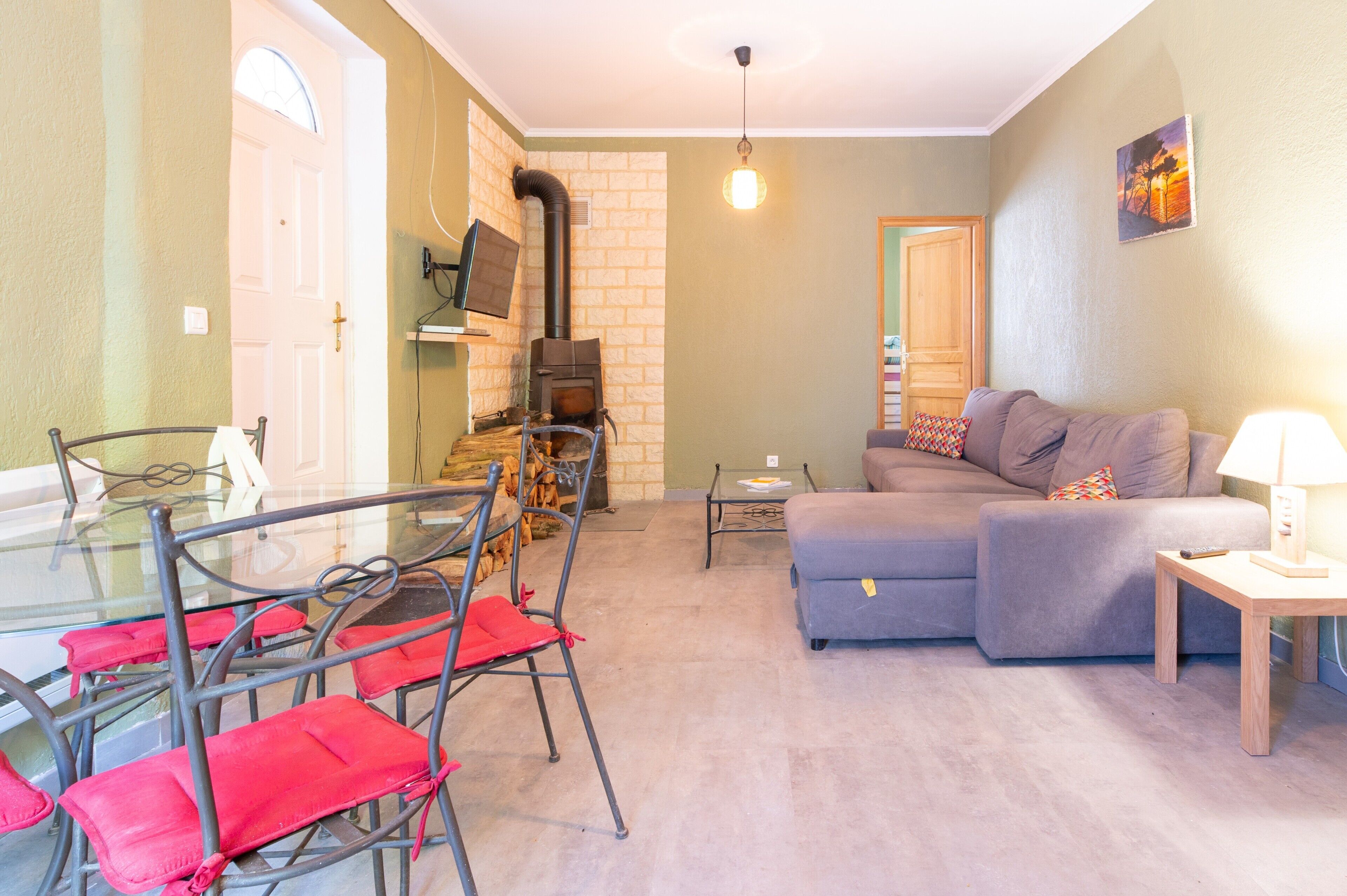 A living room with a sofa, a glass dining table with chairs, a fireplace, and a television.