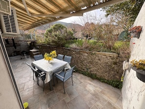 Un patio al aire libre con una mesa y sillas, un muro de piedra y vistas del paisaje circundante.