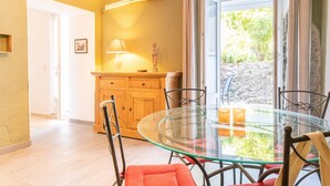 Un comedor con una mesa y sillas de vidrio, un armario de madera y vistas a áreas verdes.