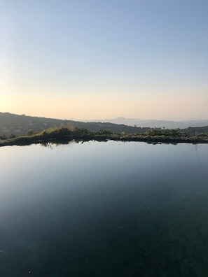 Ruhige Wasserfläche, die den Himmel und ferne Hügel spiegelt.