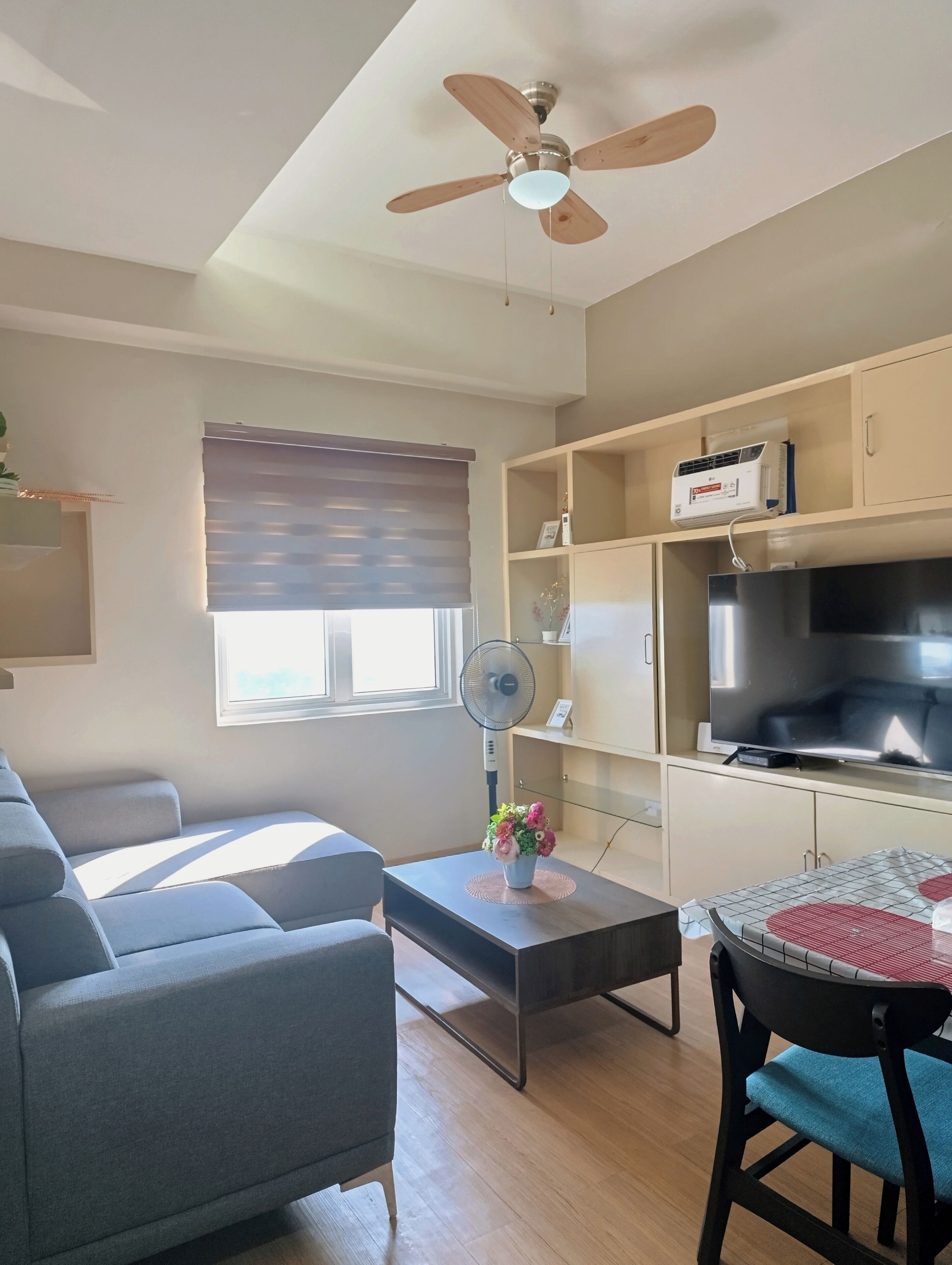 A living room with a sofa, coffee table, TV, and ceiling fan.