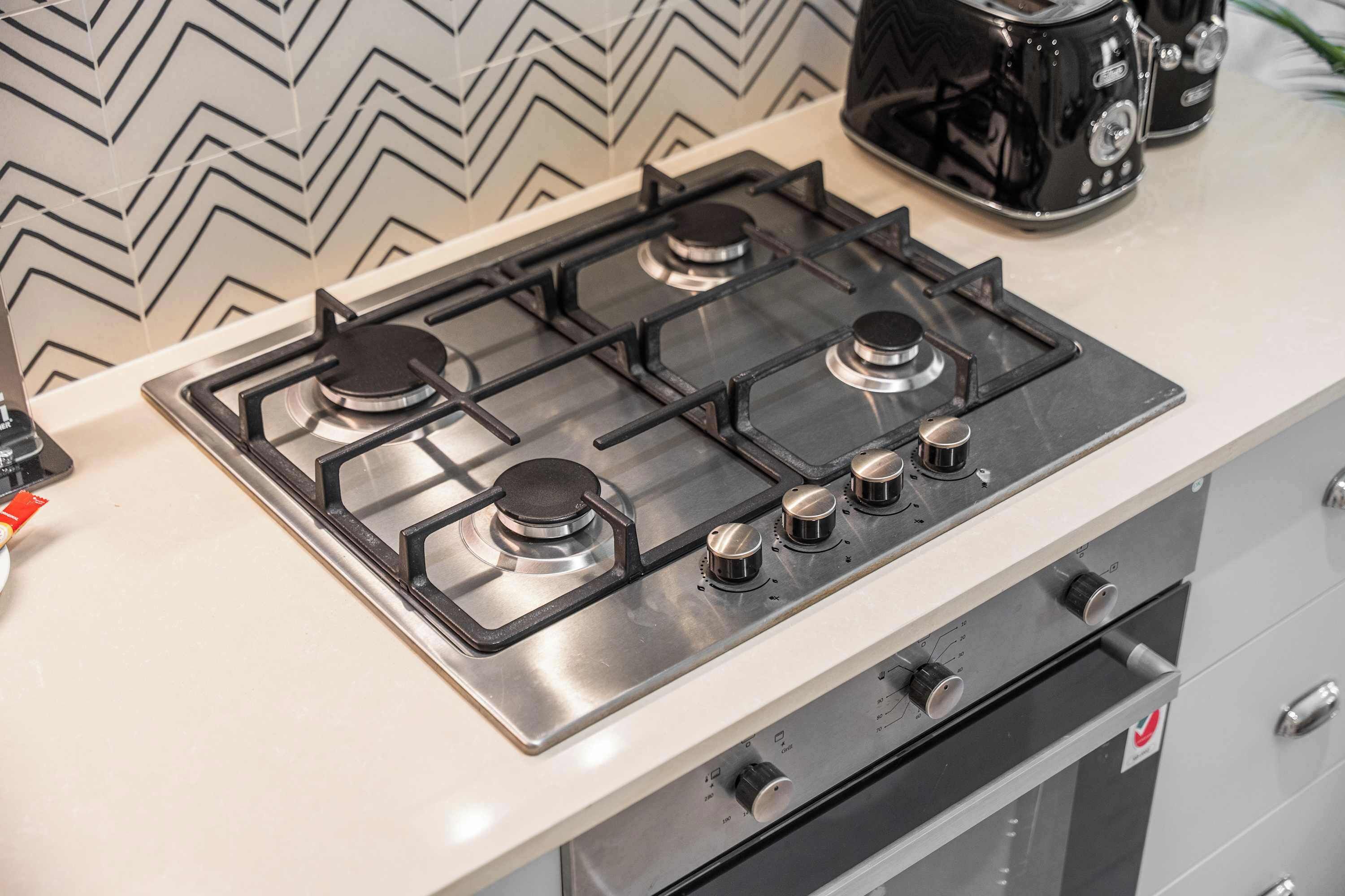 Cucina con piano cottura a gas, macchina del caffè e pannello di rivestimento moderno.