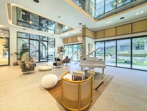 Eine geräumige Lobby mit einem Flügel, bequemen Sitzgelegenheiten und großen Fenstern mit Blick ins Freie.