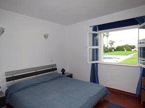 Una camera da letto con un letto, un comodino, una lampada e una finestra con tende.
