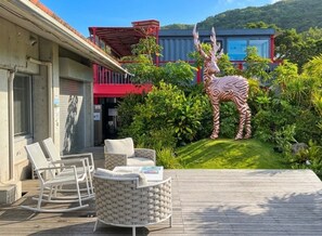 A deck with outdoor furniture, a zebra statue, and a building with a red balcony.