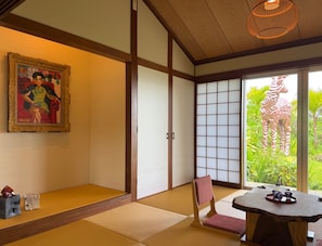 Perinteinen japanilainen huone, jossa on tatamimatto, shoji-liukuovi, taulu ja kirahvin veistos.