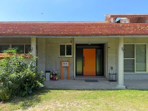 A building with a red roof, a door with an orange panel, and a small signboard.