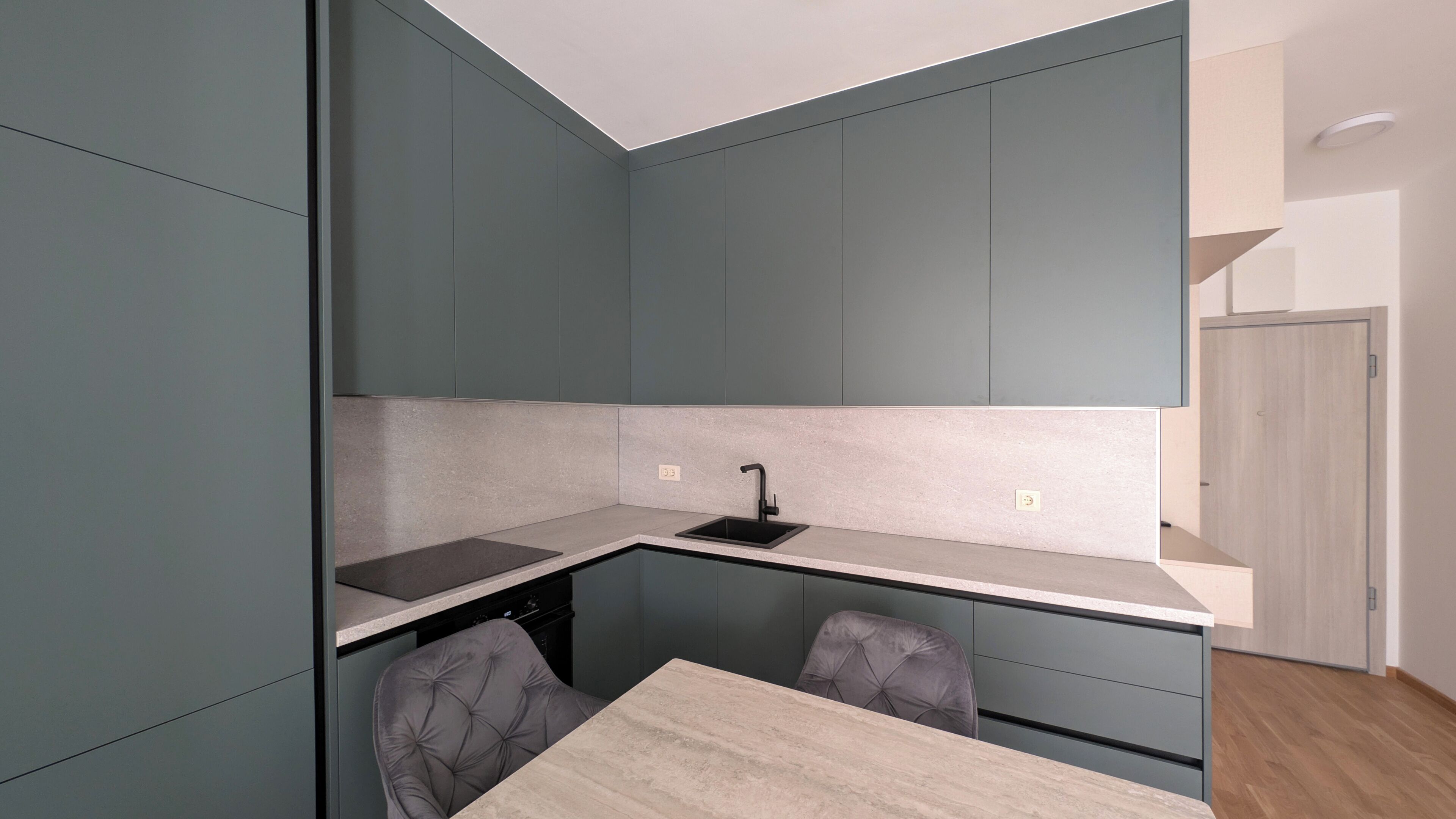 A compact kitchen with a built-in sink, a dining table, and two chairs.