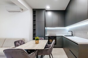 Eine moderne Küche mit Essbereich, Einbau-Schränken und einer zentralen Kochinsel.