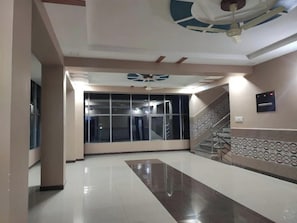 A hotel lobby with a modern design, a staircase, and a ceiling fan. - Hotel Milan Balotra (Pachpadra)