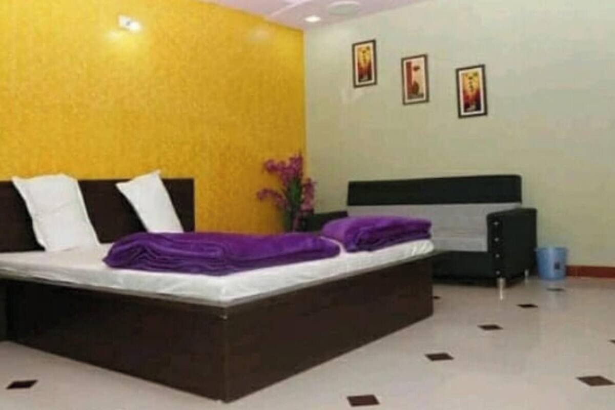 A bedroom with a bed, a nightstand, a dresser, and a wall with three framed pictures.