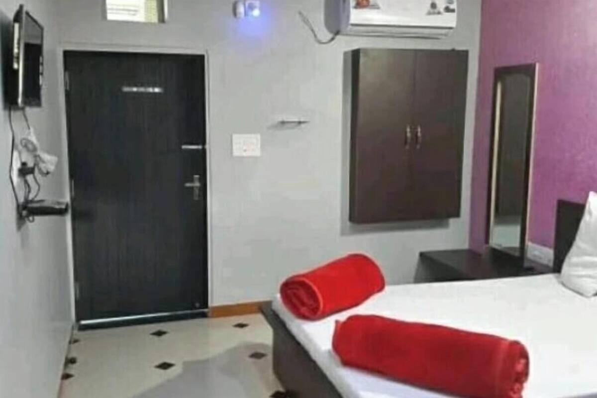 A hotel room with a bed, a wardrobe, a door, and a mirror.