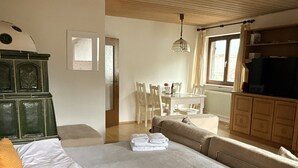 Un dormitorio con una cama grande, techo de madera, zona de comedor con sillas y televisión.