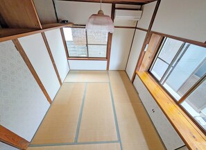Una stanza con pavimento in tatami, uno schermo scorrevole shoji, un lampadario e una finestra con vista.