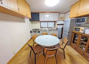 Una cucina funzionale con un tavolo rotondo, sedie in legno, un forno a microonde integrato e un frigorifero.