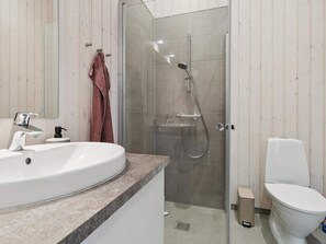A modern bathroom with a sink, toilet, and glass-enclosed shower. - 5 Star Holiday Home in Nexo (Nexø)