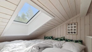 A bedroom with a skylight, a bed with white bedding, and a framed botanical print on the wall. - 5 Star Holiday Home in Nexo (Nexø)