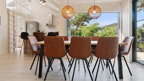 A dining area with a large table, six chairs, and two hanging light fixtures. - 5 Star Holiday Home in Nexo (Nexø)