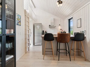 Eine moderne Küche mit einem Edelstahl-Kühlschrank, Holzbarhocker und einem Fenster, das für natürliches Licht sorgt.