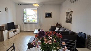Un salon avec un canapé, une télévision, une table à manger et des fleurs.