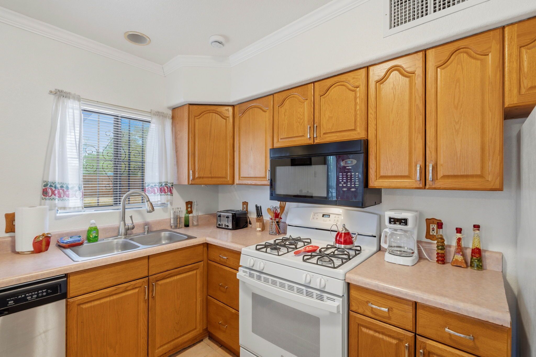 A kitchen with wooden cabinets, a gas stove, a microwave, and a dishwasher.