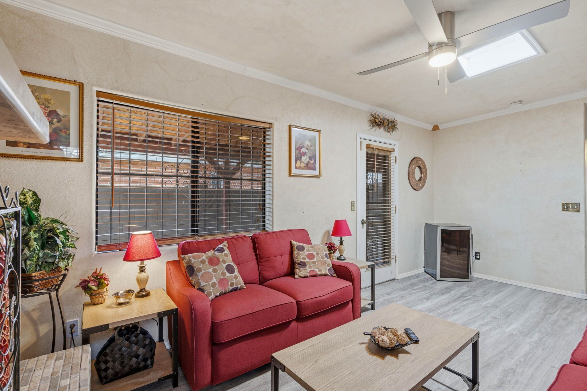 A living room with a red sofa, a wooden coffee table, a ceiling fan, and a fireplace.