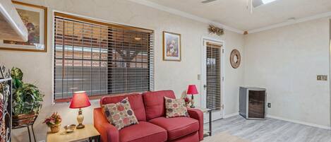 A living room with a red sofa, a wooden coffee table, a ceiling fan, and a fireplace.