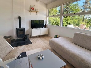 Ein Wohnzimmer mit Fernseher, Sofa und Kamin.