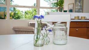 A white table with two glass vases containing flowers and a clear glass jar. - Sea-view terrace on scenic Helgenæs (Knebel)
