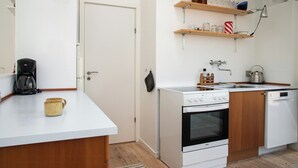 A modern kitchen with a white countertop, a coffee maker, a kettle, and a dishwasher. - Sea-view terrace on scenic Helgenæs (Knebel)